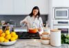 How to Choose the Right Kitchen Layout for Your Columbus Home A smiling woman preparing a meal in a modern kitchen in her Columbus home