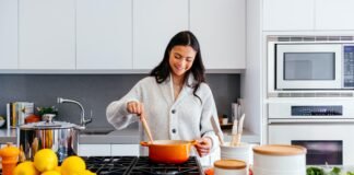 How to Choose the Right Kitchen Layout for Your Columbus Home A smiling woman preparing a meal in a modern kitchen in her Columbus home