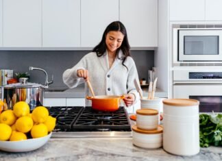 How to Choose the Right Kitchen Layout for Your Columbus Home A smiling woman preparing a meal in a modern kitchen in her Columbus home